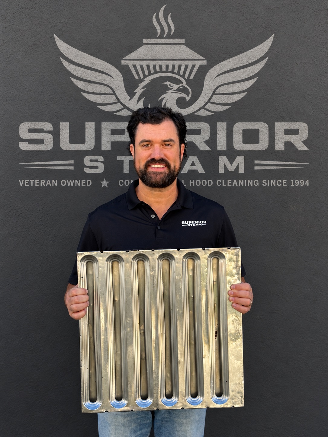 Superior Steam team member holding a commercial kitchen baffle filter